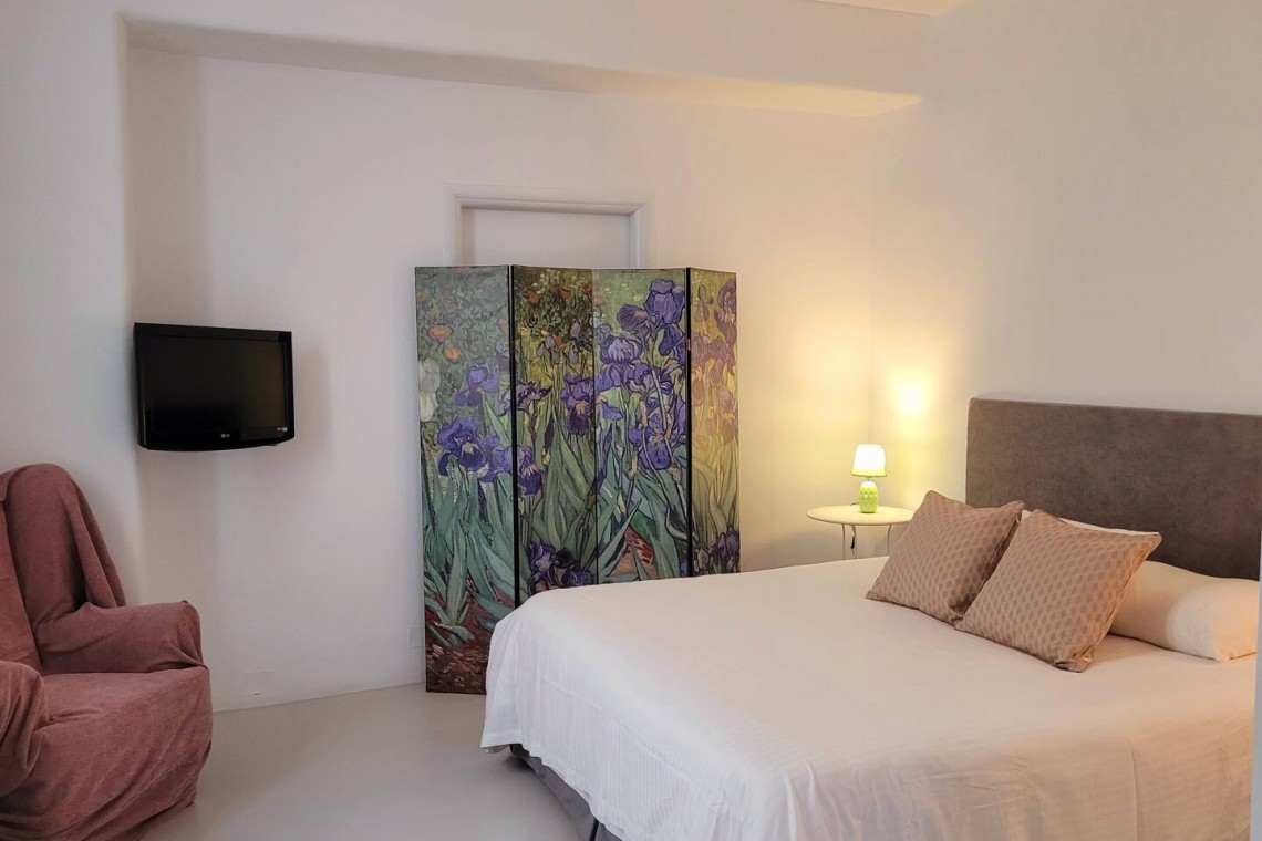 Elegant master bedroom in a villa on Tinos Island with ensuite bathroom and cozy, modern decor.