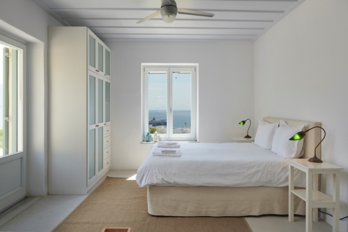 Elegant master bedroom in a villa on Tinos Island with ensuite bathroom and cozy, modern decor.