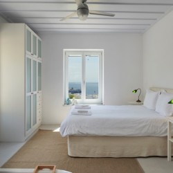 Elegant master bedroom in a villa on Tinos Island with ensuite bathroom and cozy, modern decor.
