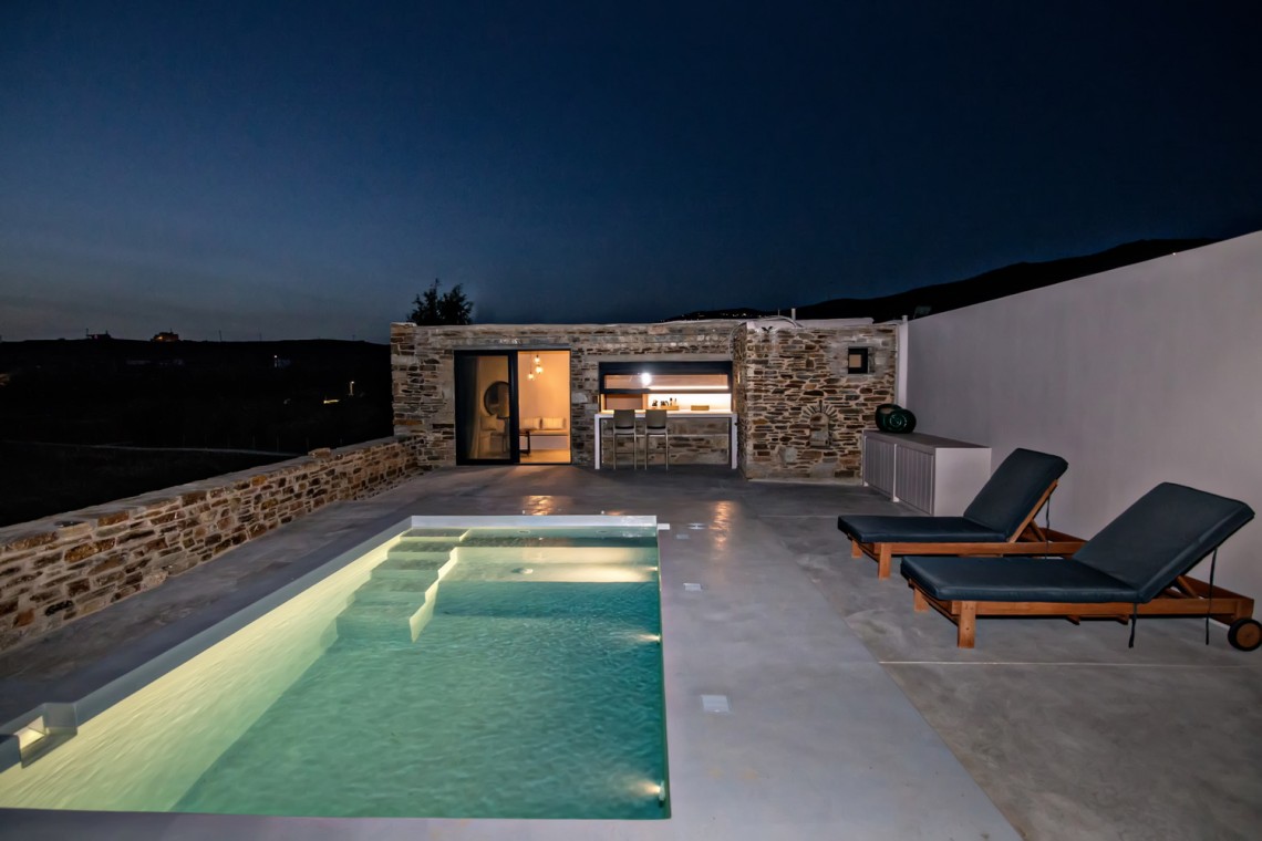 Εξωτερικός χώρος της VF Villa με ξαπλώστρες και θέα στην Κυκλαδίτικη φύση.