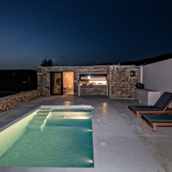 Εξωτερικός χώρος της VF Villa με ξαπλώστρες και θέα στην Κυκλαδίτικη φύση.