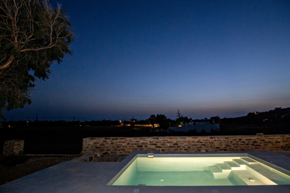Εξωτερικός χώρος της VF Villa με ξαπλώστρες και θέα στην Κυκλαδίτικη φύση.