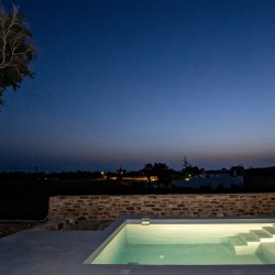 Εξωτερικός χώρος της VF Villa με ξαπλώστρες και θέα στην Κυκλαδίτικη φύση.